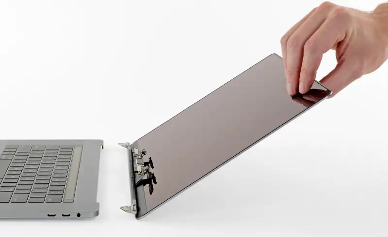 Tehnician care demonteaza panoul displayului de pe topcase-ul unui MacBook Pro — display-ul e ridicat din rama de aluminiu pentru inlocuire, hinge-ul si flex cables sunt vizibile, exemplu de operatiune profesionala la divizia noastra de service