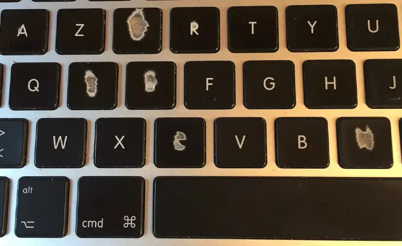Macro pe o tastatura MacBook cu mai multe taste (E, R, C, V, B) ale caror litere imprimate s-au sters complet sau partial — exemplu de tastatura aftermarket cu cerneala UV de calitate inferioara care nu rezista uzurii normale